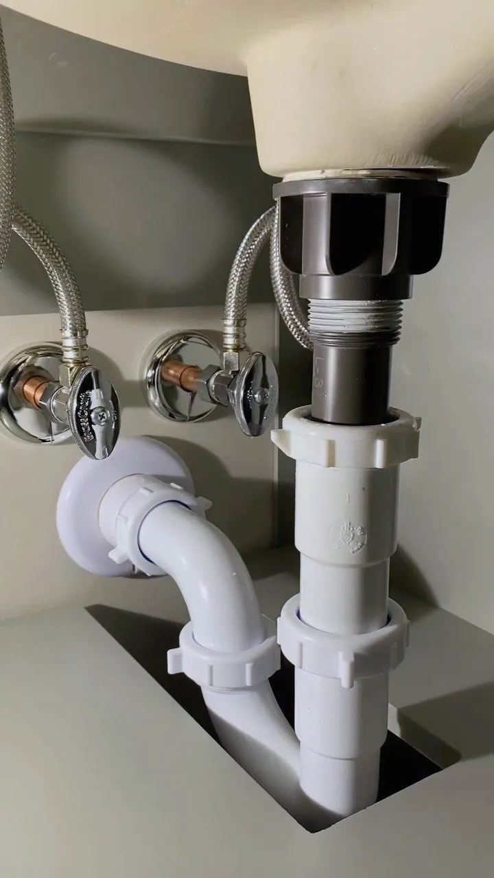 Sifón y llaves de paso nuevos bajo un lavabo